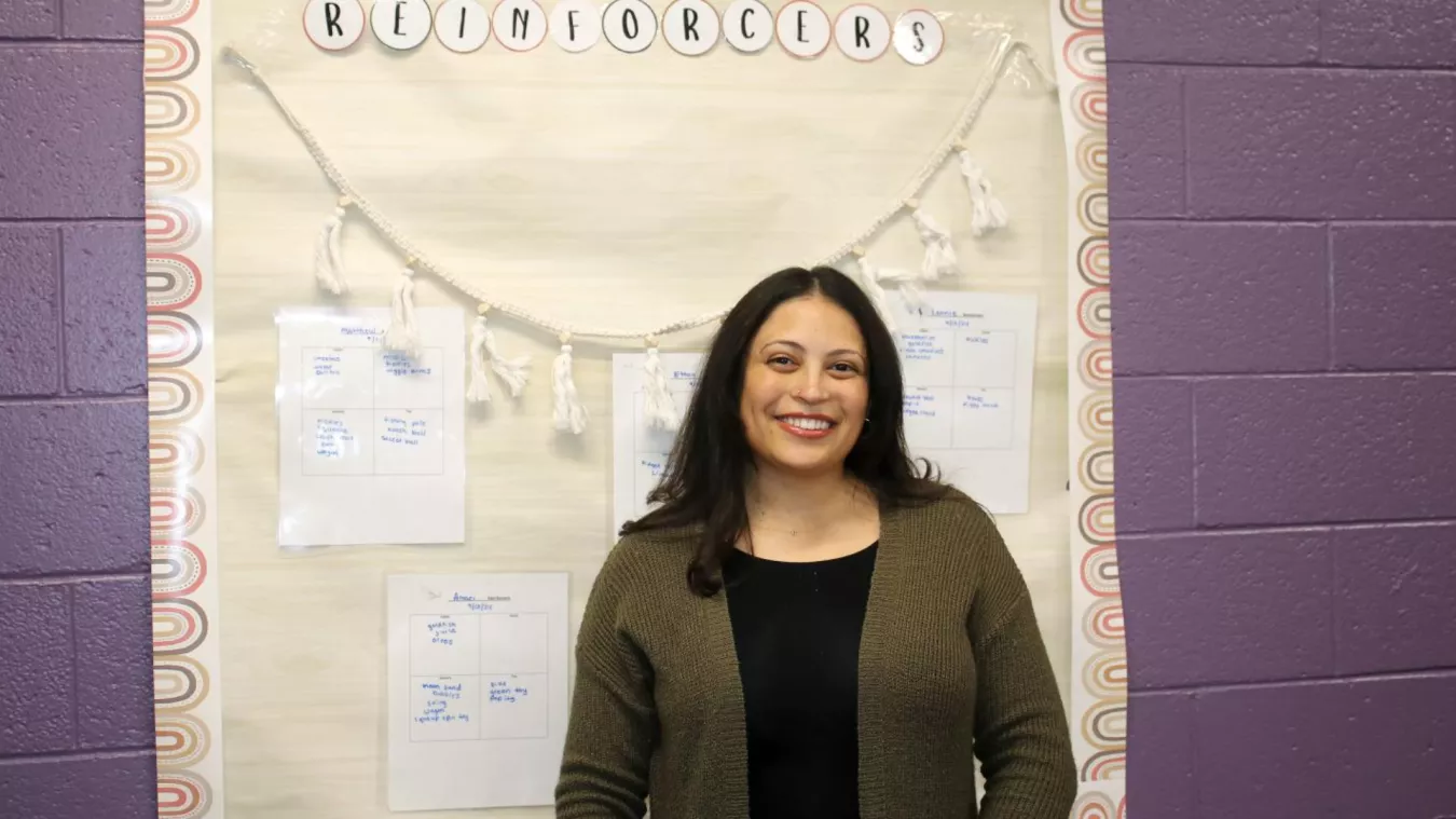 Christina Paraprofessional Association Vice President Rhonika Daniels stands in front of a poster