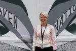 Katie Birmingham stands in front of a Raven Nation mural