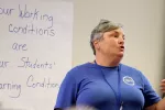 Christina Paraprofessional Association President Gretchen Loose stands in front of a whiteboard that says Your Working Conditions Are Your Students' Learning Conditions