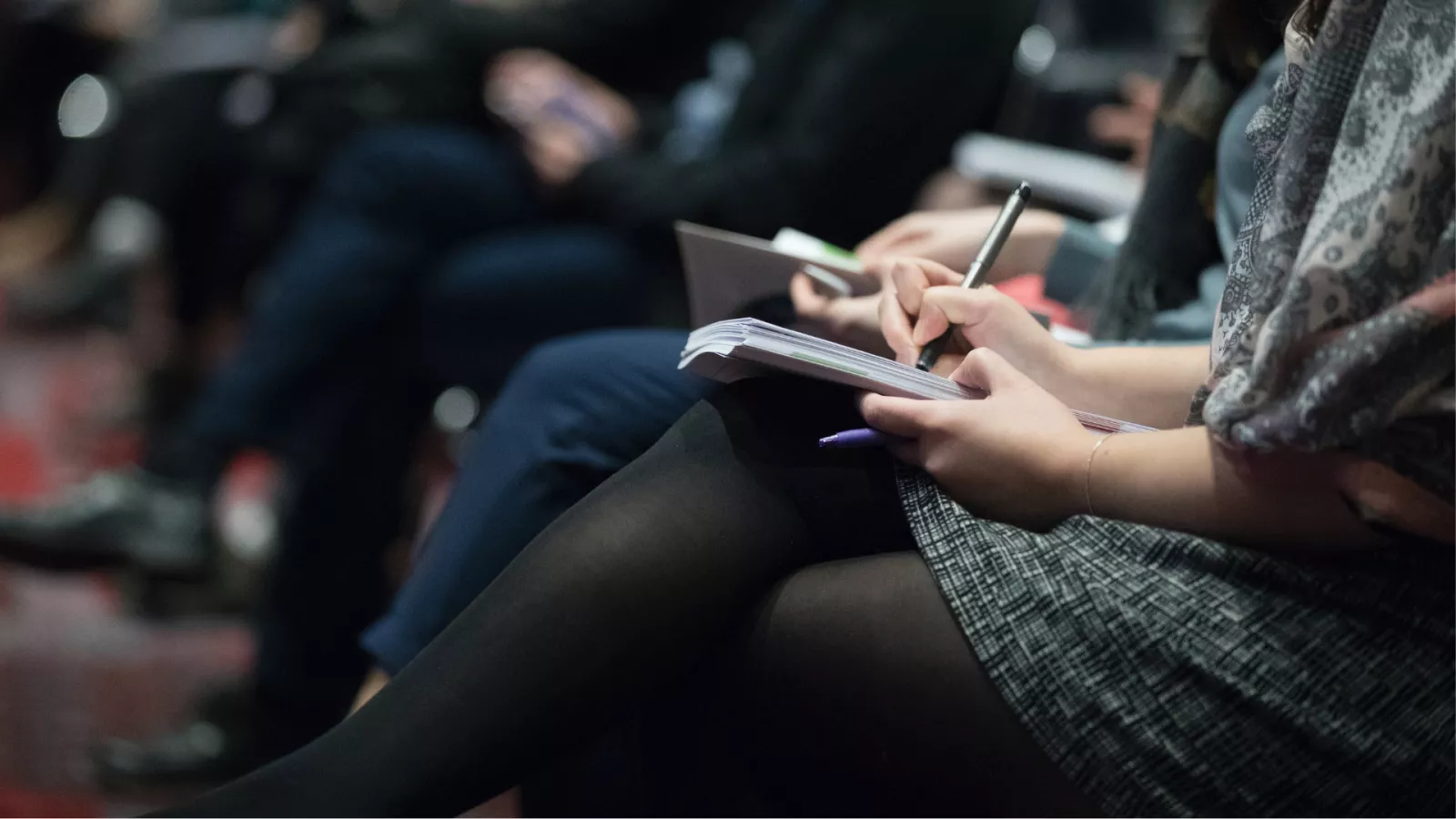 group of people sitting in crowd taking notes