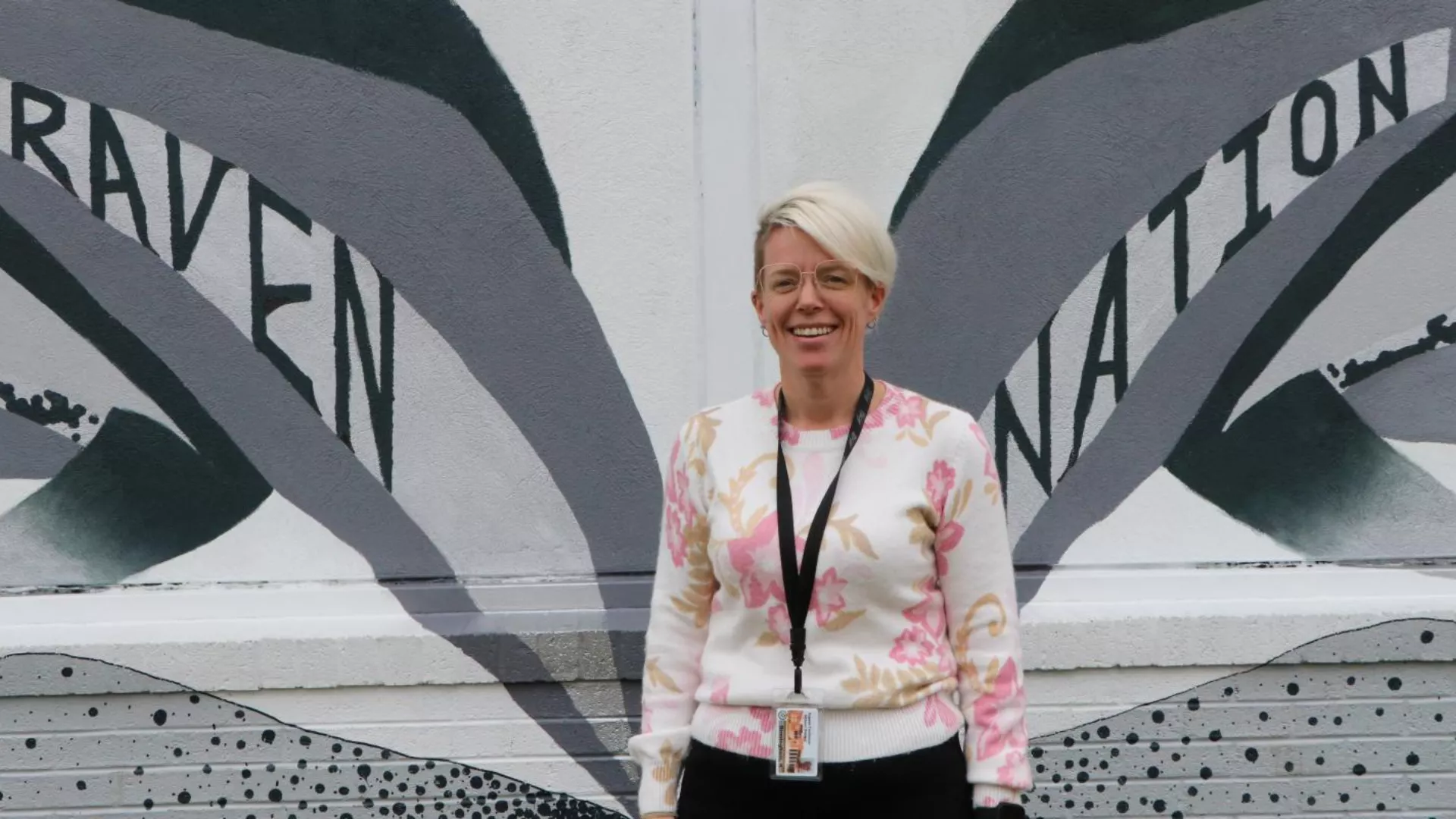 Katie Birmingham stands in front of a Raven Nation mural