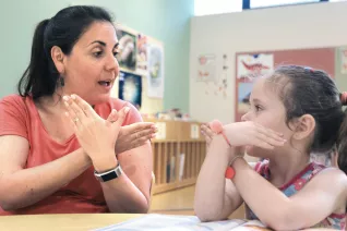 educator uses sign language with a young student