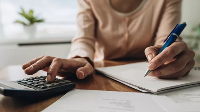 A person is at a desk; you can see their hand hovering over a calculator