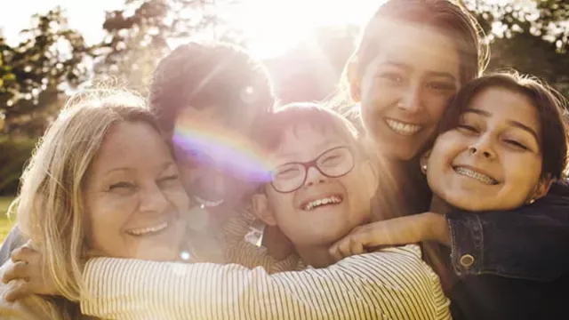 a family hugging with the sun shining bright behind them